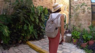 Elinde kamera olan genç bir kadın dar bir sokakta yürüyor ve fotoğraf çekiyor. Mutlu bir kız Jaffa, İsrail 'de tatilinin tadını çıkarıyor.