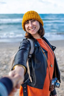 Sahilde erkek arkadaşıyla gezinin tadını çıkaran bir kadın, dikiz manzaralı. Seyahat eden çift. Kız ve erkek el ele tutuşuyor. Sahilde yürü..