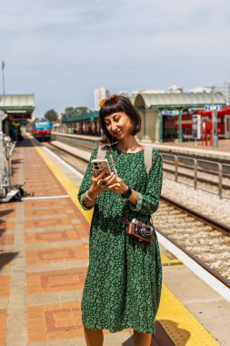 İstasyonun platformunda kameralı ve sırt çantalı genç ve güzel bir kız. İyi yolculuklar..