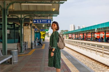 İstasyonun platformunda kameralı ve sırt çantalı genç ve güzel bir kız. İyi yolculuklar..