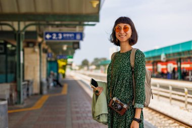 İstasyonun peronunda kameralı ve sırt çantalı genç ve güzel bir kız var ve tren saatine bakıyor. İyi yolculuklar..