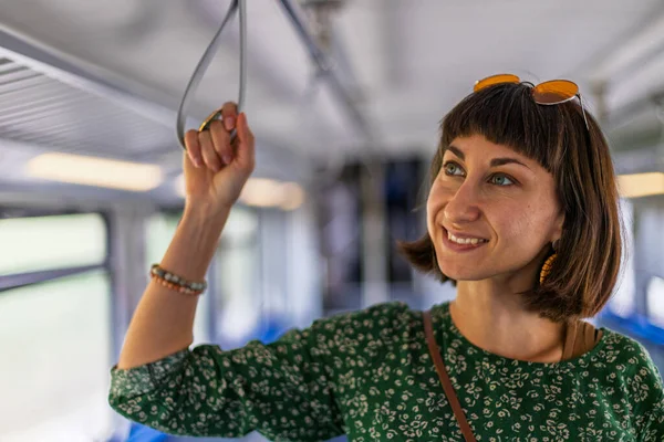 Kız toplu taşıma araçlarını kullanıyor. Trende duran kız. Her gün işe giderken toplu taşıma araçlarını kullanan mutlu ve çekici bir kadın..