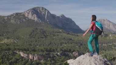 Bir kız kollarını neşe, memnuniyet ve zaferle kaldırır. Dağın zirvesinde bir kız zirveye ulaşmasını kutluyor.