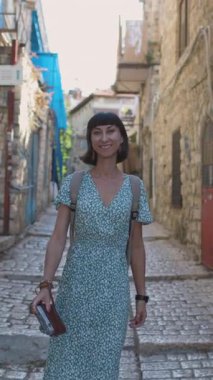 Dikey çekim. Ağır çekim, kameralı kadın turist tarihi şehir Safed, Israel 'de dar bir sokakta yürüyor, macera