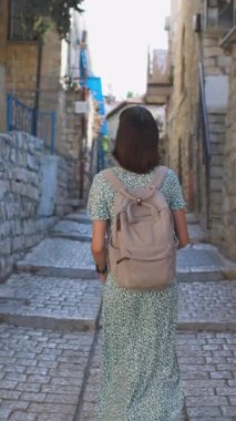 Dikey çekim. Çekici bir turist eski kasabanın caddesinde yürüyor ve simgelerin fotoğraflarını çekiyor. İçerik oluşturuluyor