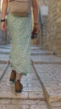 Dikey çekim. Ağır çekim, dikiz aynası, kameralı kadın turist İsrail 'in tarihi şehri Safed' de dar bir sokakta yürüyor.