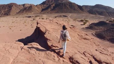 Çölde yürüyen sırt çantalı bir kadın. Çölde gezinti ve yürüyüş. Arkadan bak. Timna Ulusal Parkı. İsrail. Turist