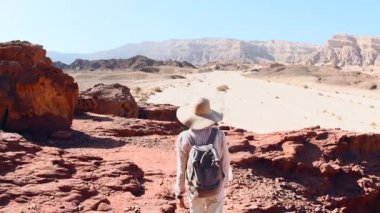 Çölde yürüyen sırt çantalı bir kadın. Çölde gezinti ve yürüyüş. Arkadan bak. Timna Ulusal Parkı. İsrail. Turist