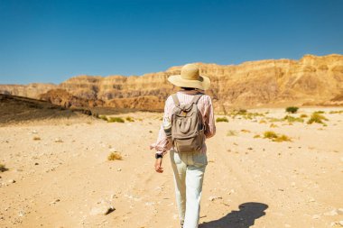Timna Ulusal Parkı 'nın çarpıcı doğal güzelliği. Sırt çantalı bir kadın yürüyüşçü çölde yürüyor, kırmızı kayaların ve kanyon geçitlerinin tadını çıkarıyor. Timna Ulusal Parkı. İsrail.