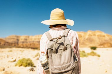 Timna Ulusal Parkı 'nın çarpıcı doğal güzelliği. Sırt çantalı bir kadın yürüyüşçü çölde yürüyor, kırmızı kayaların ve kanyon geçitlerinin tadını çıkarıyor. Timna Ulusal Parkı. İsrail.