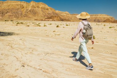 Çölde yürüyen sırt çantalı bir kadın. Çölde gezinti ve yürüyüş. Arkadan bak. Timna Ulusal Parkı. İsrail. Çölde bir turist.