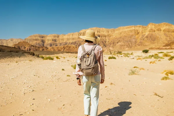 Timna Ulusal Parkı 'nın çarpıcı doğal güzelliği. Sırt çantalı bir kadın yürüyüşçü çölde yürüyor, kırmızı kayaların ve kanyon geçitlerinin tadını çıkarıyor. Timna Ulusal Parkı. İsrail.