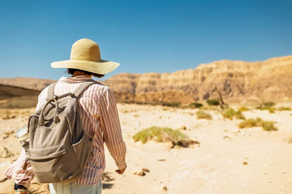 Timna Ulusal Parkı 'nın çarpıcı doğal güzelliği. Sırt çantalı bir kadın yürüyüşçü çölde yürüyor, kırmızı kayaların ve kanyon geçitlerinin tadını çıkarıyor. Timna Ulusal Parkı. İsrail.