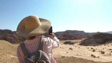 Sırt çantalı bir kız çöl manzarası fotoğrafı çekiyor. Gezgin blogcu. Çöl gezisi. Timna Ulusal Parkı. İsrail. Bir turist.