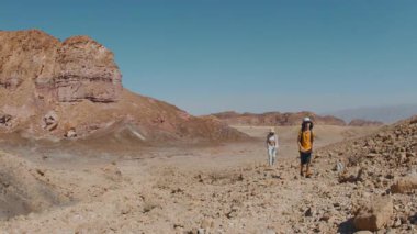 İki aktif gezgin mavi gökyüzüne karşı çölde geziniyor. Anne ve çocuk yürüyüşe çıktı. Yaz kampı. Timna Ulusal Parkı