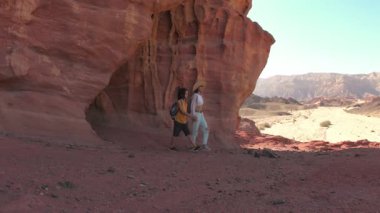 Sırt çantalı bir çocuk dağ yolunda annesinin yanında yürüyor. Aile gezisi. Timna Ulusal Parkı. Çocuk aktif olarak...