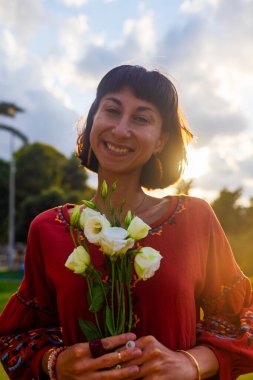 Açık havada elinde bir buket çiçekle gülümseyen kadın portresi. Kıza bir buket çiçek verilir. Bir yaz akşamı romantik bir ruh hali olan genç bir kadının yakın çekimi..