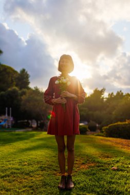 Gün ışığında bir buket taze bahar çiçeğiyle gülümseyen kadın yüzünü kapat. Çiçek tomurcuklarından hoşlanan mutlu kızın yüzü. Romantik ruh hali. Çiçek buketli kadın.
