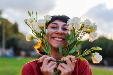 Açık havada elinde bir buket çiçekle gülümseyen kadın portresi. Kıza bir buket çiçek verilir. Bir yaz akşamı romantik bir ruh hali olan genç bir kadının yakın çekimi..