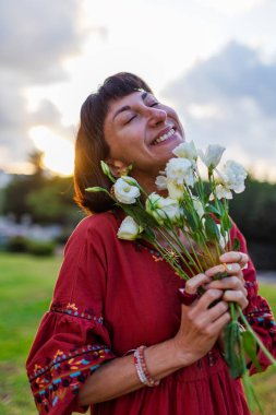 Açık havada elinde bir buket çiçekle gülümseyen kadın portresi. Kıza bir buket çiçek verilir. Bir yaz akşamı romantik bir ruh hali olan genç bir kadının yakın çekimi..