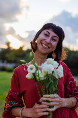 Gün ışığında bir buket taze bahar çiçeğiyle gülümseyen kadın yüzünü kapat. Çiçek tomurcuklarından hoşlanan mutlu kızın yüzü. Romantik ruh hali. Çiçek buketli kadın.