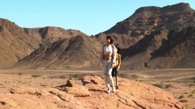 Yürüyüşe çıkmış bir anne ve çocuk. Elinde harita ve sırt çantası olan bir çocuk annesinin yanında yürüyor. Aile gezisi. Timna Ulusal Parkı. Şey...