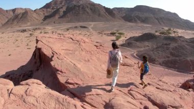 Bir çocuk ve annesi çölde yürüyorlar. Çocuk aktif olarak zaman geçiriyor. Yaz tatili. Aile yürüyüşü. Timna Ulusal
