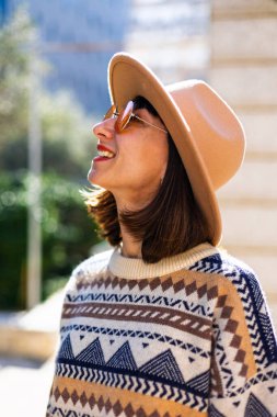 Açık havada şık turuncu gözlük takan güzel beyaz bir kadının moda portresi. Şık giyinmiş bir kızın portresi. Kentsel tarzda bir kız. Yaşam tarzı, bulanık arkaplanda şehir görünümü.