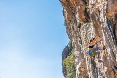 Kadın kaya tırmanışı. Güçlü kız kayaya tırmanıyor. Olağanüstü bir hobi. Zor bir kaya tırmanış rotasının üstesinden gelmek. Yükseklik korkusunu yenmek. Kaya tırmanışı çabaları. Duygusal kız..