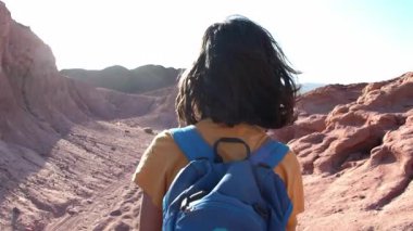 Çölde yürüyüş. Sırt çantalı bir çocuk. Sırt çantasıyla dağlarda yürüyüş yapan bir çocuk. Bir çocuk patikada yürüyor.