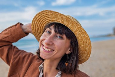 Yağmurdan sonra plajda yürürken şapkalı genç bir kadının görüntüsü. Kız sahildeki anın tadını çıkarıyor. Romantik ruh hali.