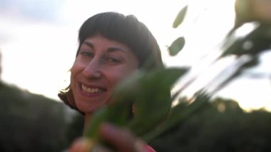 Bir kıza bir buket çiçek verilir. Kocaman bir buket çiçekle genç, çekici, gülümseyen bir kadının yakın plan portresi.