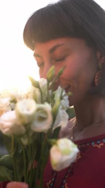 Dikey çekim. Kız çiçeklerin ve gülümsemelerin kokusunu içine çekiyor. İlk randevu. Bir buket çiçekli kız.