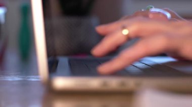 Bilgisayarda daktilo eden ve dokunmatik pedi kullanan birinin yakın çekimi. Tanımlanamayan bir serbest yazar internette geziniyor.
