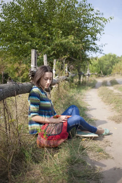 Chica con libros y mochila sentada en el parque . — Foto de Stock