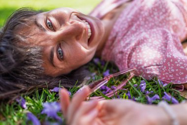 Yaz havası. Yeşil çimlerin ve çiçeklerin üzerinde yatan genç bir kadın. Yaz havası. Kız dışarıda vakit geçiriyor. Doğanın ve tatilin tadını çıkar. Mutlu kadın..