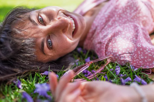 Yaz havası. Yeşil çimlerin ve çiçeklerin üzerinde yatan genç bir kadın. Yaz havası. Kız dışarıda vakit geçiriyor. Doğanın ve tatilin tadını çıkar. Mutlu kadın..