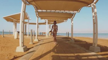 Ölü Deniz 'de tatilin tadını çıkaran bir kız. Ölü Deniz plajı boyunca koşan bir kadın. İsrail. Deniz kenarında güzel bir kadın.