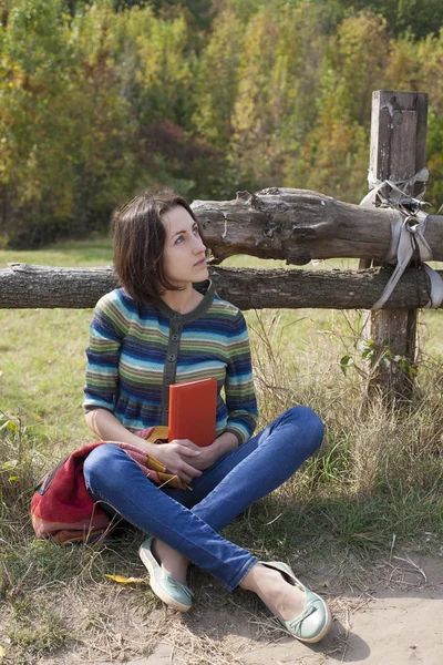 Resenären flicka sitter med en bok om naturen. — Stockfoto