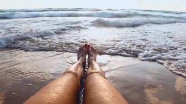 Mayo giymiş bir kadın okyanusun kenarındaki temiz kumsalda güneşleniyor ve dinleniyor. Sahilde bir kız okyanus dalgalarının tadını çıkarıyor. Kapat