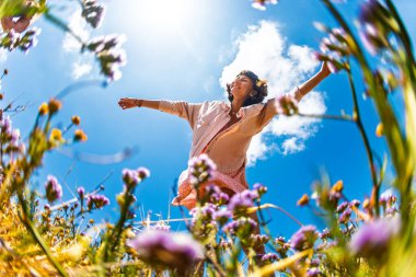 Çiçekler arasında doğanın tadını çıkaran mutlu bir kadın. Açık havada. Moda tarzı..