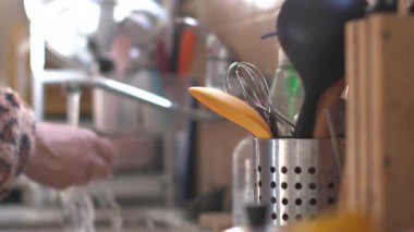 Bir adam kaşığı yıkıyor ve onu alet çantasına koyuyor. Sıcak mutfak..
