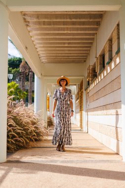 Açık havada, sokakta yürüyen, elbise ve şapka giymiş güzel esmer bir kadının uzun bir portresi. moda ve tarz kavramı.