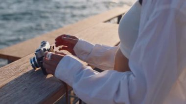 Deniz kenarında kamerası olan bir kız. Bir fotoğrafçı kamerayı ayarlar. Modaya uygun bir kadın analog bir film kamerası tutuyor. Seyahat ve