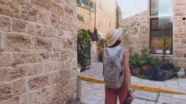 Genç ve çekici bir kadın eski Jaffa şehrinde kamerayla gezip fotoğraf çekiyor. Seyahat ve macera konsepti.