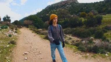 Maceralar ve seyahatler. Sırt çantalı bir çocuk dağ yolunda yürüyor. Çocuklarla seyahat..