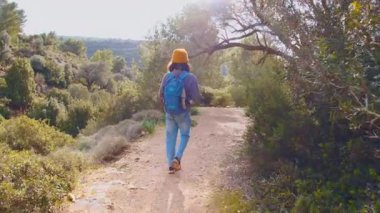 Maceralar ve seyahatler. Sırt çantalı bir çocuk dağ yolunda yürüyor. Çocuklarla seyahat..