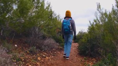 Maceralar ve seyahatler. Sırt çantalı bir çocuk dağ yolunda yürüyor. Çocuklarla seyahat..