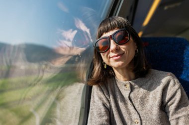 Tren yolculuğu. Genç bir kadın trene biniyor, güzel manzaraya hayran ve pencereden dışarı bakıyor. Genç bir kız tren yolculuğunun tadını çıkarıyor..