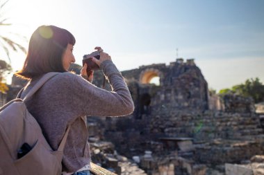 Blogu ve sosyal medyası için sırt çantalı şık bir turist. İsrail 'de antik taş kalıntıları yakınında bir turist. Beit She'an. Kameralı bir kız..
